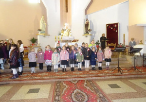 Grupa dzieci stoi pod ołtarzem w kościele.